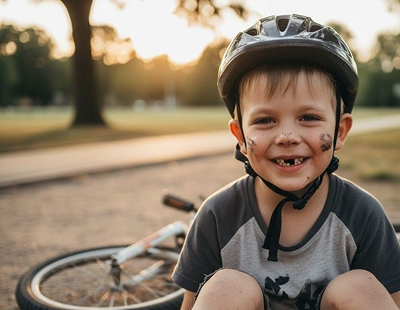 Smiling muddy boy wearing helmet by bicycle