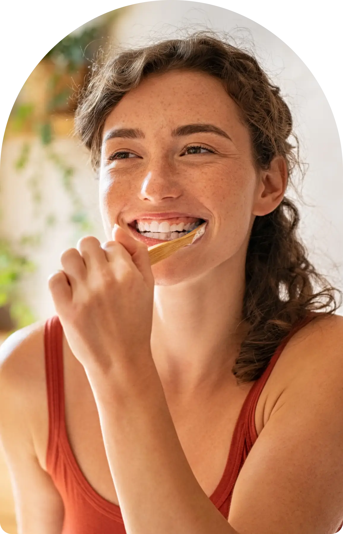 Woman smiling while brushing her teeth.
