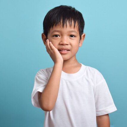 Young boy in white shirt touching cheek