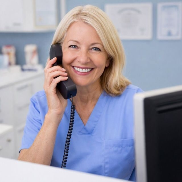 Smiling healthcare worker in blue scrubs on phone